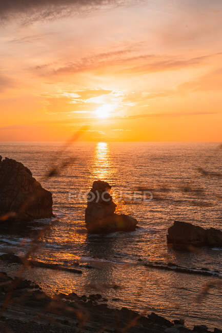 Incredibile scenario tranquillo del tramonto sul mare ondulato increspato con rocce sotto cielo nuvoloso colorato in estate sera a Liencres Cantabria Spagna — Foto stock