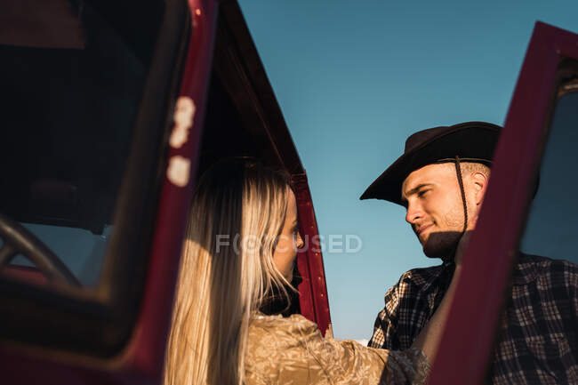 Casal amoroso olhando um para o outro no carro vintage estacionado na natureza no dia ensolarado — Fotografia de Stock