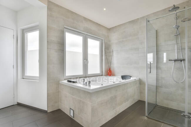 Design de interiores elegante casa de banho com telhas de mármore cinza e janelas equipadas com unidade de chuveiro e banheira de luxo no apartamento moderno — Fotografia de Stock