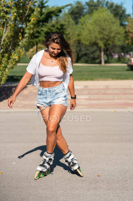 Jovem fêmea em patins mostrando acrobacias na estrada na cidade no verão — Fotografia de Stock