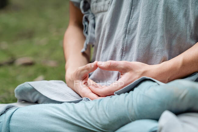 Cropped unrecognizable bald man in traditional clothes sitting on grass in Lotus pose and meditating during kung fu training in forest — Stock Photo
