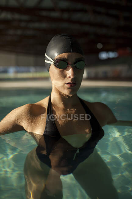 Jovem mulher bonita no passeio da piscina interior, com maiô preto — Fotografia de Stock