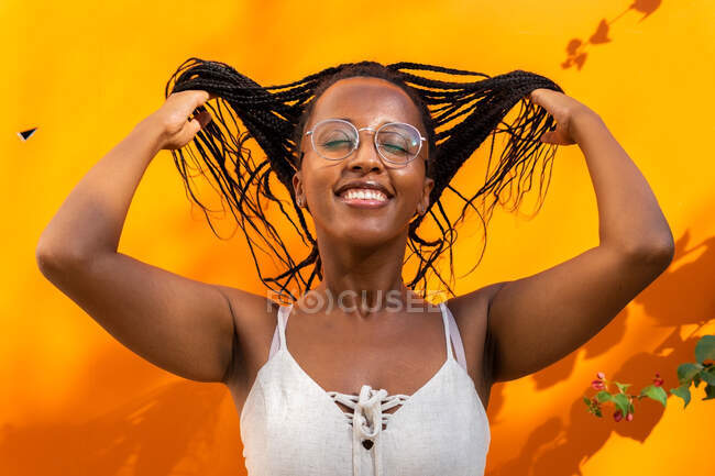Afro-americano fêmea jogar longo trançado cabelo no vívido amarelo fundo no Barcelona — Fotografia de Stock