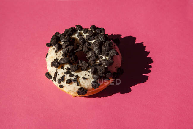 White donuts coated oreo chocolate cookie pieces on pink background — Stock Photo