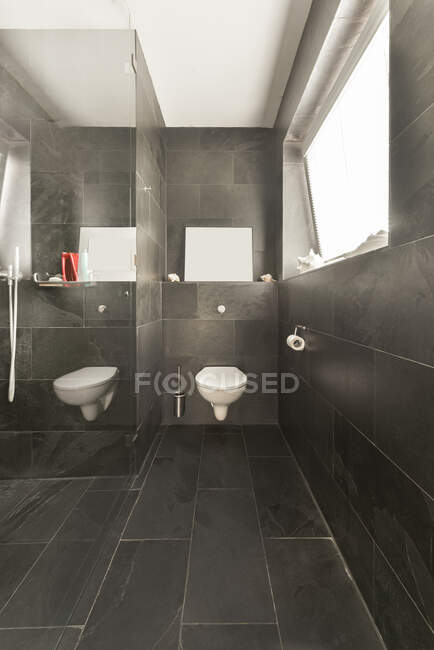 Intérieur de la salle de bain moderne avec toilettes murales blanches et murs gris et plancher conçu dans un style minimal — Photo de stock