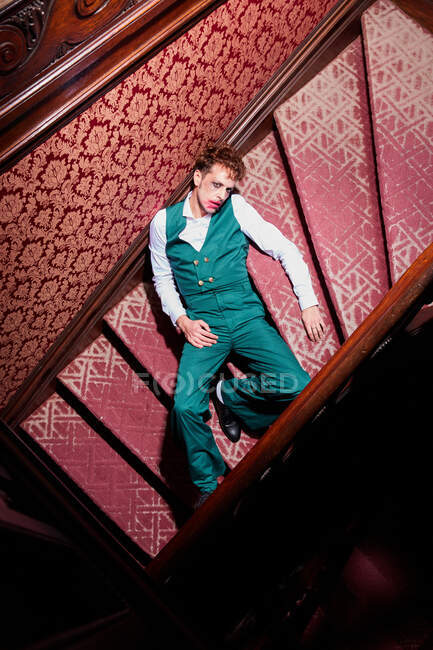 Сверху выразительный мужчина-актер, лежащий на лестнице и притворяющийся мертвым во время выступления — стоковое фото