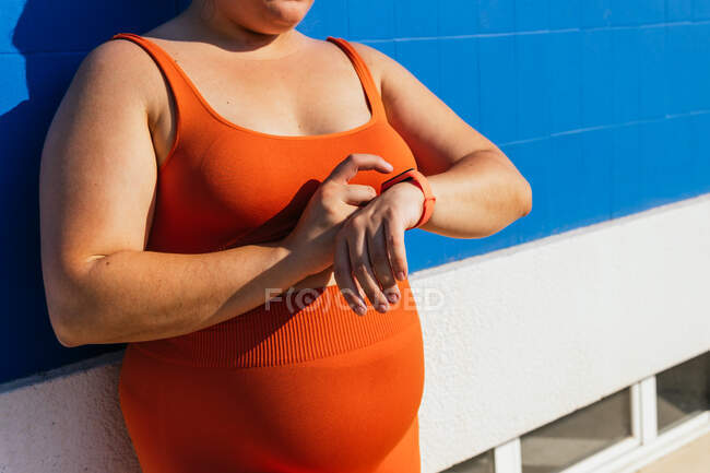 Crop unrecognizable sportswoman with curvy body watching heart rate on wearable tracker during workout on street — Stock Photo