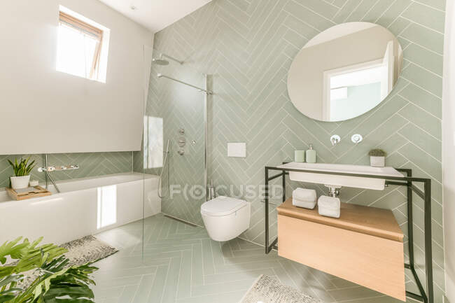 Weiße Keramik-Waschbecken und Toilette in der Nähe von Dusche und Badewanne im modernen Badezimmer mit pastellgrünen Wänden — Stockfoto
