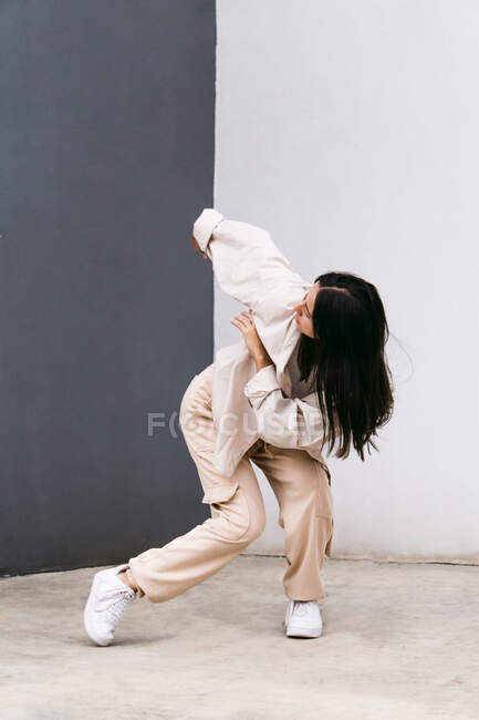 Повна довжина творча жіноча танцівниця в білому одязі танцює на міській вулиці під час виступу — стокове фото