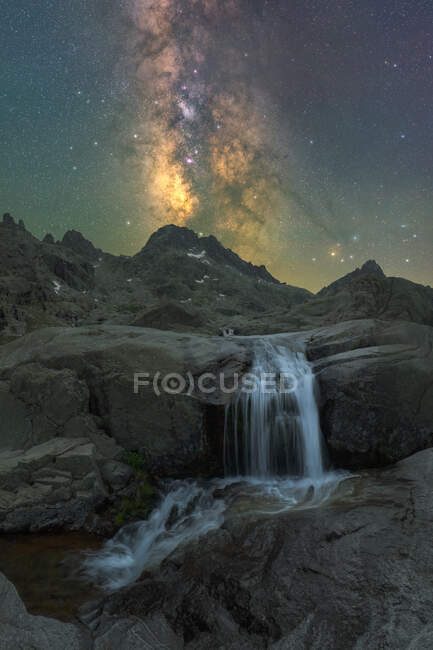 Spectacular view of high rough mounts with cascade and river under starry sky with galaxy in evening — Stock Photo
