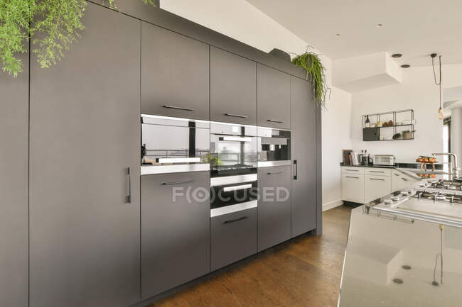 Cocina abierta en apartamento de estilo loft moderno con paredes blancas y techo en apartamento espacioso - foto de stock