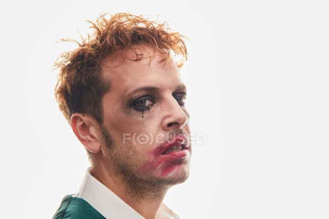Excêntrico ator masculino espantado com maquiagem manchada realizando em fundo branco — Fotografia de Stock