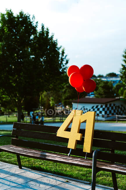 Красные шарики и номер 41 на скамейке во время празднования дня рождения в городе в солнечный день — стоковое фото