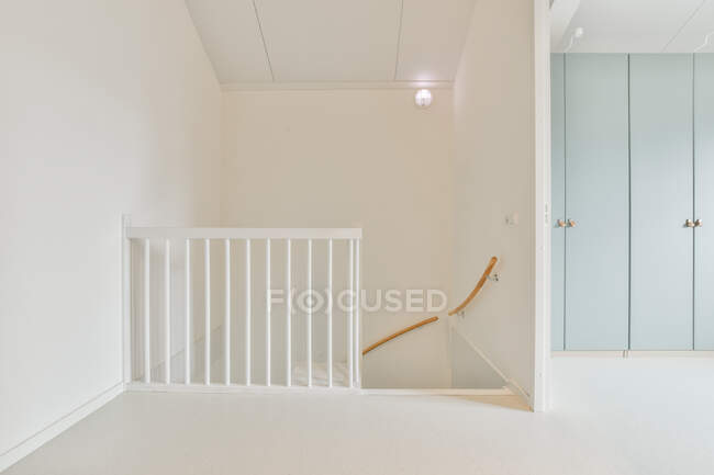 Diseño interior de estilo minimalista con paredes blancas y barandilla en la escalera en el piso superior del apartamento moderno - foto de stock