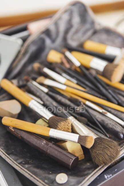 Alto ángulo de manojo de cepillos de maquillaje y suministros cosméticos colocados en la bolsa - foto de stock