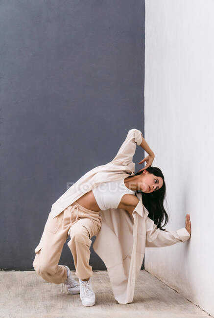 Творческая танцовщица танцует на городской улице и опирается на стену во время выступления — стоковое фото