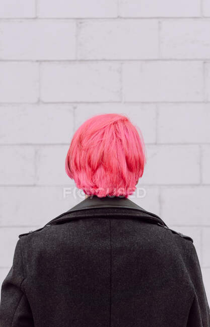 Back view crop unrecognizable female with dyed hair standing near white wall — Stock Photo