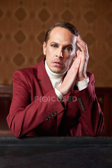 Serious pensive adult male theater artist with makeup and in elegant outfit looking at camera while thinking over decision — Stock Photo