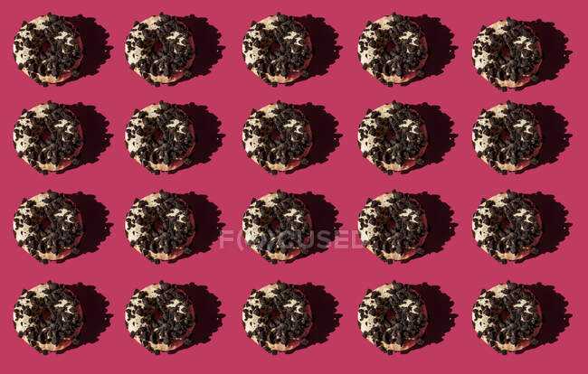 Vista superior de muitos donuts brancos cobertos com pedaços de biscoito oreo no fundo rosa — Fotografia de Stock