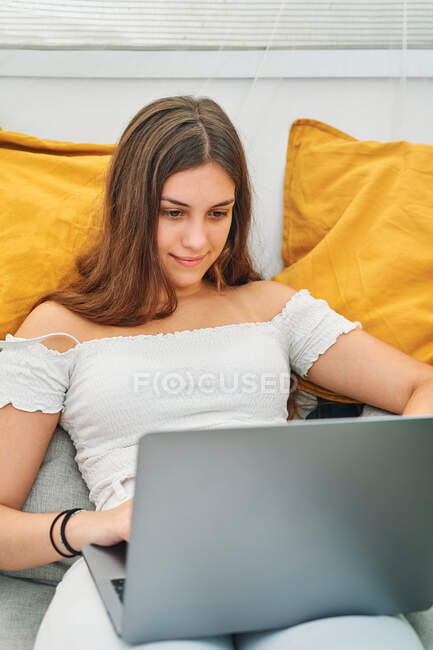 Young female sitting at table and surfing Internet on netbook enjoying summer weekend in backyard tent — Stock Photo