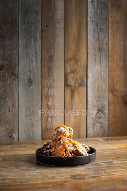 Гарячі смачні курячі крильця з соусами розміщені на круглої тарілці на дерев'яному столі — стокове фото