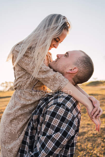 Namorado legal abraçando namorada sorridente enquanto olha um para o outro — Fotografia de Stock
