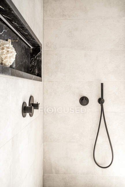 Interior do banheiro com cabine de chuveiro com torneira preta alças e mangueira em paredes brancas — Fotografia de Stock