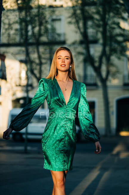 Mulher despreocupada em vestido verde na moda de pé com braços estendidos na rua e olhando para a câmera — Fotografia de Stock