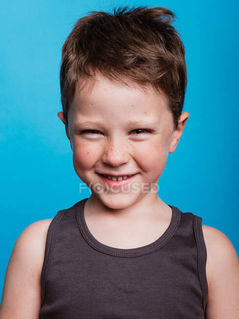 Content adorable preteen boy looking at camera on bright blue background in studio — Stock Photo