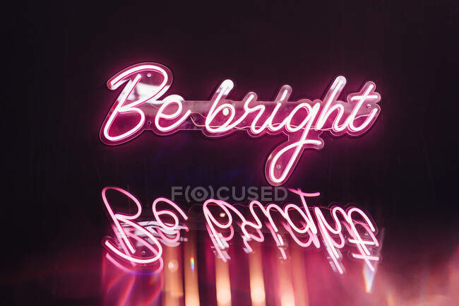 Diseño creativo de letrero rosa con el título de Be Bright reflejado con letras onduladas al atardecer - foto de stock