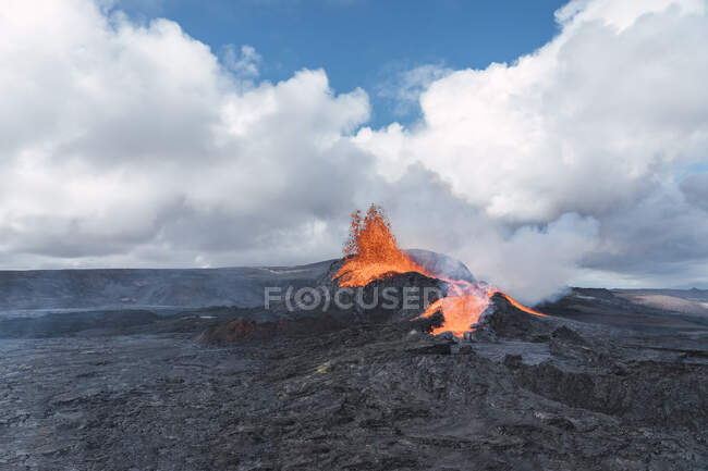 Malerischer Blick auf den Fagradalsfjall mit schnellem Feuer und Lava unter diffusem Rauch in Bergen mit flauschigen Wolken in Island — Stockfoto