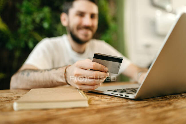 Кадрирование мужчина делает покупку с пластиковой картой для заказа во время онлайн-покупок через ноутбук — стоковое фото