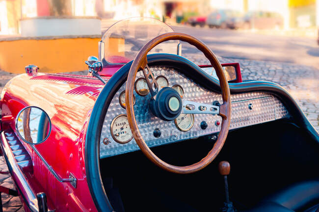 Red vintage vehicle with brown steering wheel parked on cobbled street on sunny summer day — Stock Photo