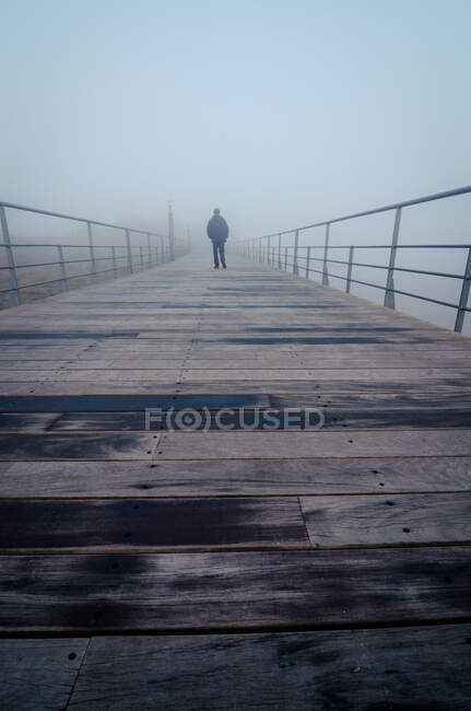 Unrecognizable person strolling on wooden quay into thick fog in morning in Lisbon, Portugal — Stock Photo