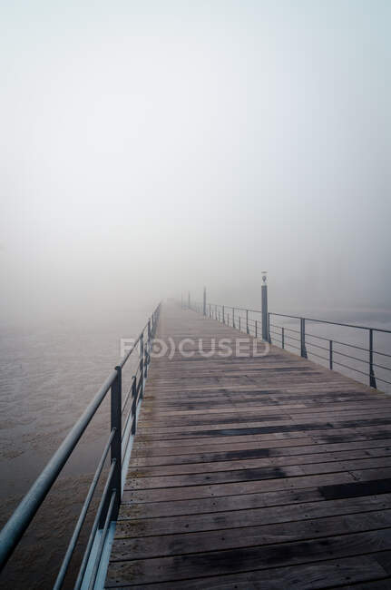 Terraço de madeira com grades de metal localizado na margem do rio Tejo em neblina manhã em Lisboa, Portugal — Fotografia de Stock