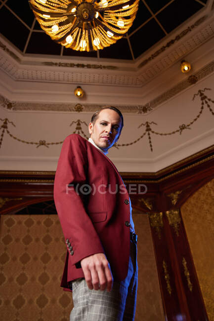 From below of classy adult male theater artist in burgundy jacket and with makeup looking at camera with arrogance — Stock Photo