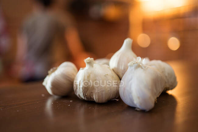 Gros plan de têtes d'ail fraîches placées sur le comptoir en bois dans la cuisine pour la préparation des aliments — Photo de stock