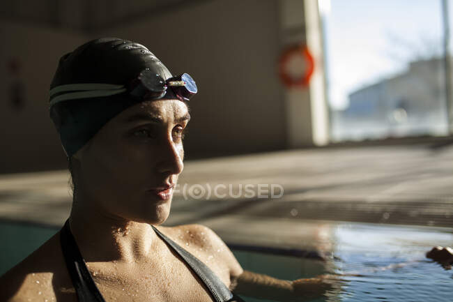 Jovem mulher bonita na piscina interior, vestindo maiô preto — Fotografia de Stock