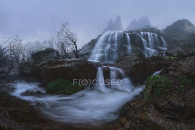 Каскади з потоками швидкої води на нерівній горі під туманним небом восени — стокове фото