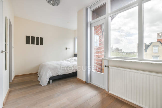 Diseño interior de estilo minimalista dormitorio con cama y balcón puerta y ventana en casa moderna con arquitectura geométrica inusual - foto de stock