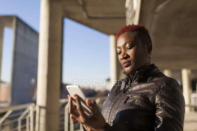 Vista lateral da bela mulher afro se comunicando com seu smartphone — Fotografia de Stock