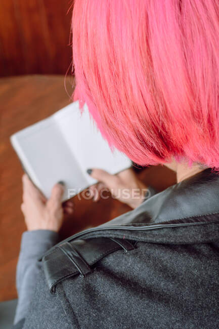 Von oben eine anonyme Frau in lässiger Kleidung, die ein geöffnetes Notizbuch auf einem Holztisch hält — Stockfoto