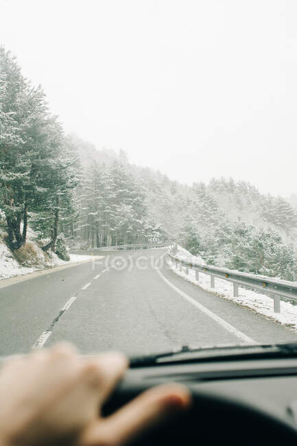 Through windshield view of crop unrecognizable traveler driving transport on roadway on Pico Aunamendi in Pyrenees Mountains on winter day in Navarre Spain — Stock Photo