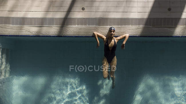 Bella donna nuotatore giovane con berretto costume da bagno nero e occhiali da bagno pugnalato sul bordo, vista aerea con drone — Foto stock