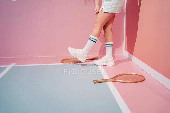 Side view of crop unrecognizable stylish female athlete in knee socks with tennis racket walking on sports ground — Stock Photo