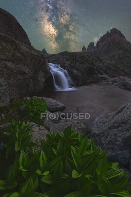 Herrliche Landschaft aus schäumend plätscherndem Wasserfall, der durch raues felsiges Gelände unter nächtlichem Sternenhimmel mit hell leuchtender Milchstraße fließt — Stockfoto