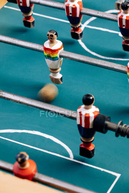 Alto angolo di dettaglio di calcio balilla retrò con figurine in miniatura di legno di giocatori su barre metalliche — Foto stock