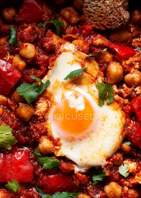 Top view of chakchouka with sunny side up egg in delicious tomato sauce with rye bread piece in bowl — Stock Photo