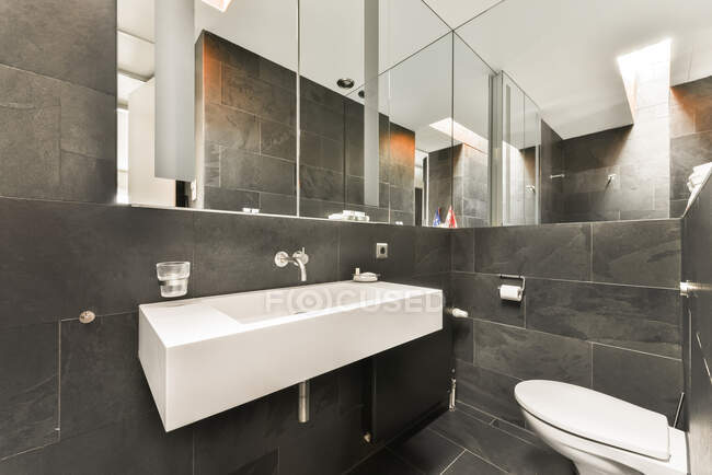 Lavabo bianco in bagno contemporaneo con pareti e pavimento piastrellati neri — Foto stock