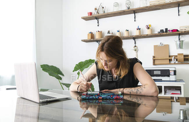 Grafikerin mit Netbook und Tablet mit Stift bei der Arbeit am Projekt am Tisch im Kreativstudio — Stockfoto